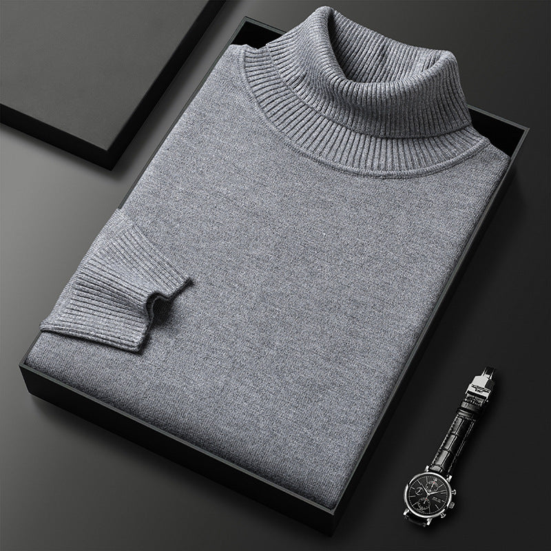 Grauer Rollkragenpullover gefaltet in einer schwarzen Box, daneben eine Armbanduhr mit Lederarmband; Rippkragen und Rippbündchen am Ärmel sichtbar. 5