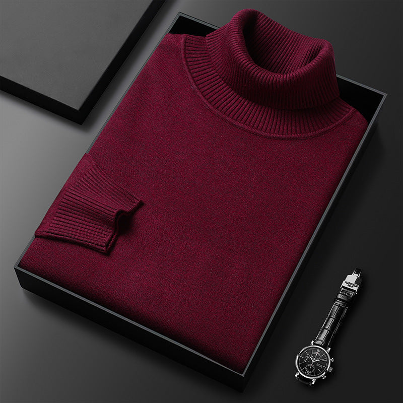 Weinroter Rollkragenpullover gefaltet in einer schwarzen Box, daneben eine Armbanduhr mit Lederarmband; Rippkragen und Rippbündchen sichtbar. 7