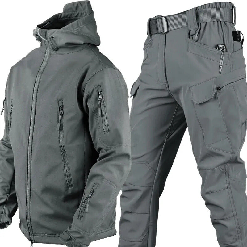 Graues Set aus Kapuzenjacke und Cargohose mit Gürtel, freigestellt, Jacke mit Reißverschlusstaschen an Brust und Ärmeln.