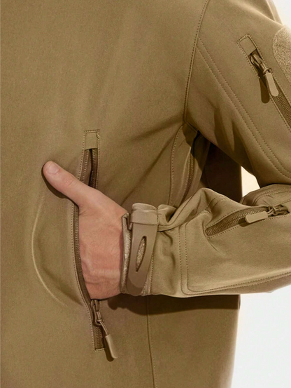 Detailaufnahme der sandfarbenen Jacke mit Hand in der Seitentasche, Reißverschluss, Ärmelbündchen mit Klettverschluss und Ärmeltasche.