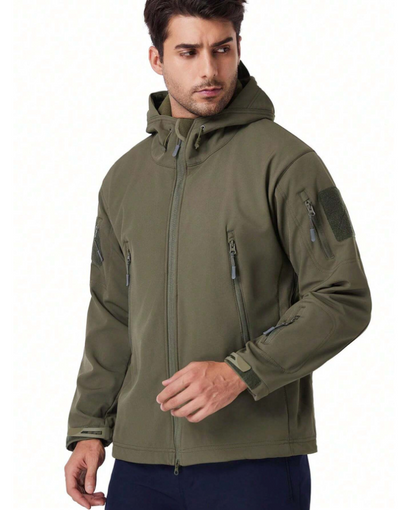 Grüne Jacke in schräger Frontansicht mit Ärmeltasche, Klettfläche und Klettverschluss an den Bündchen.